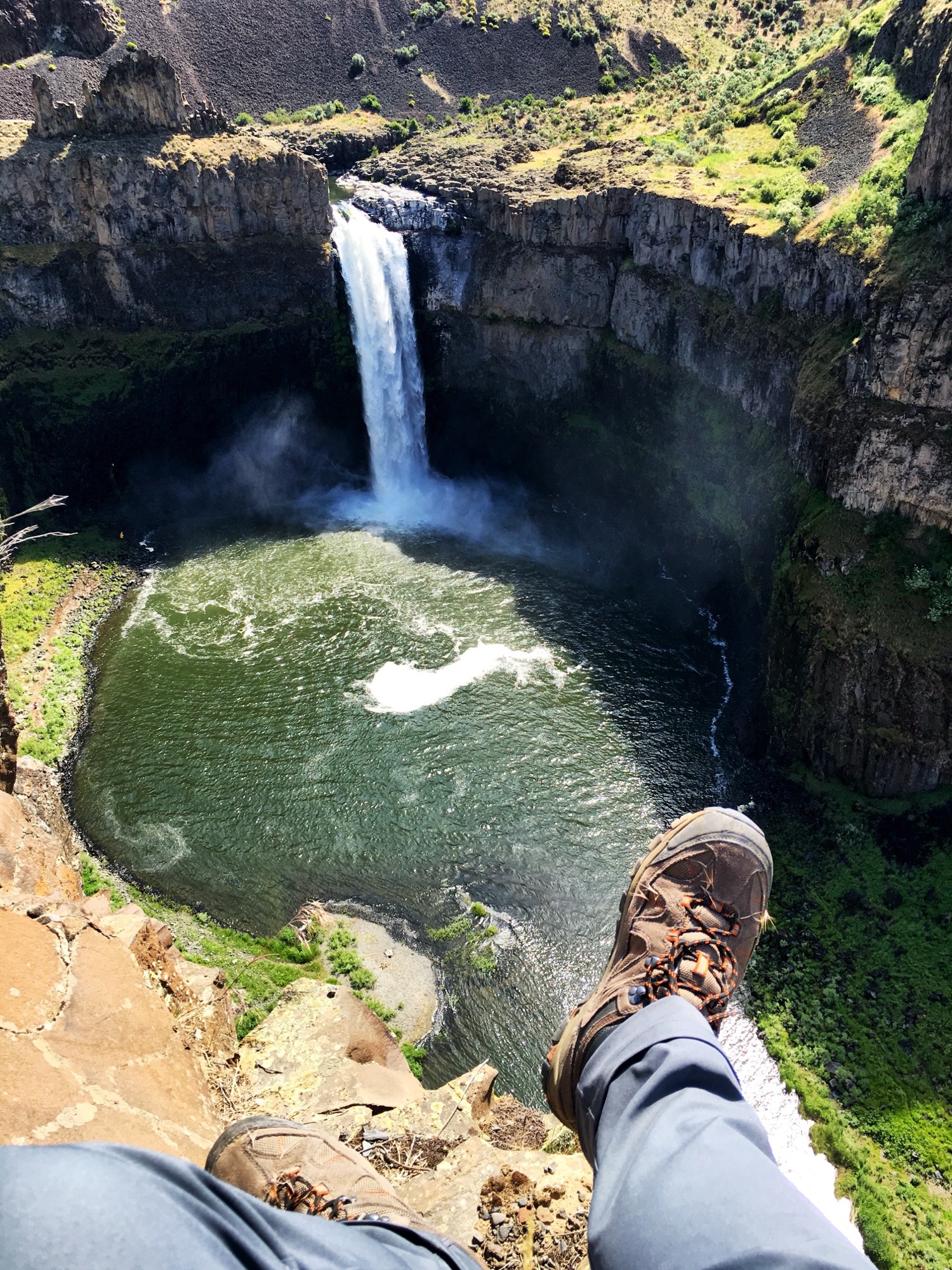 Dangling feet over the edge of a cliff with Palouse Falls roaring far below