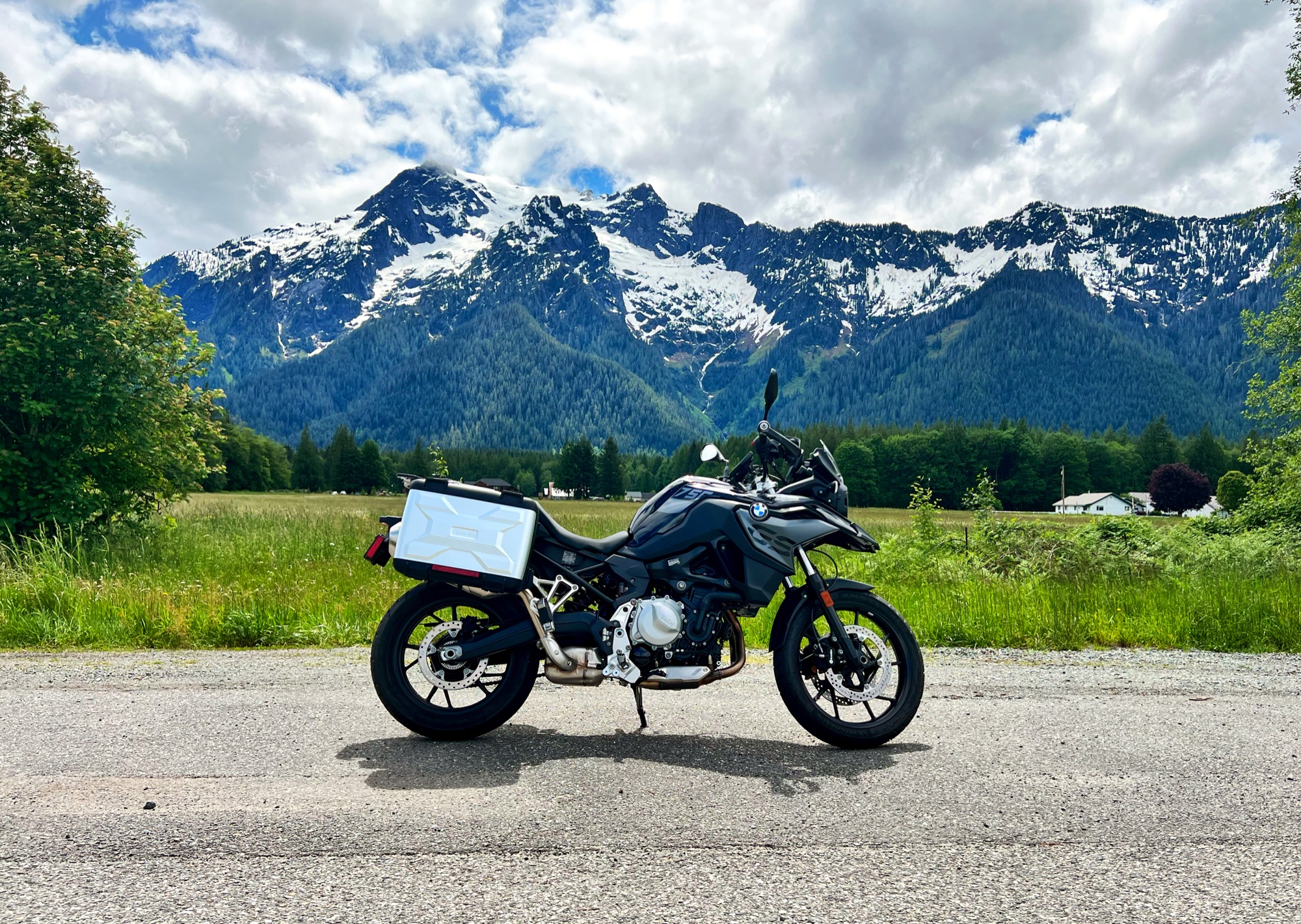 Motorcycle parked on a road with dramatic snowy mountain peaks in the background