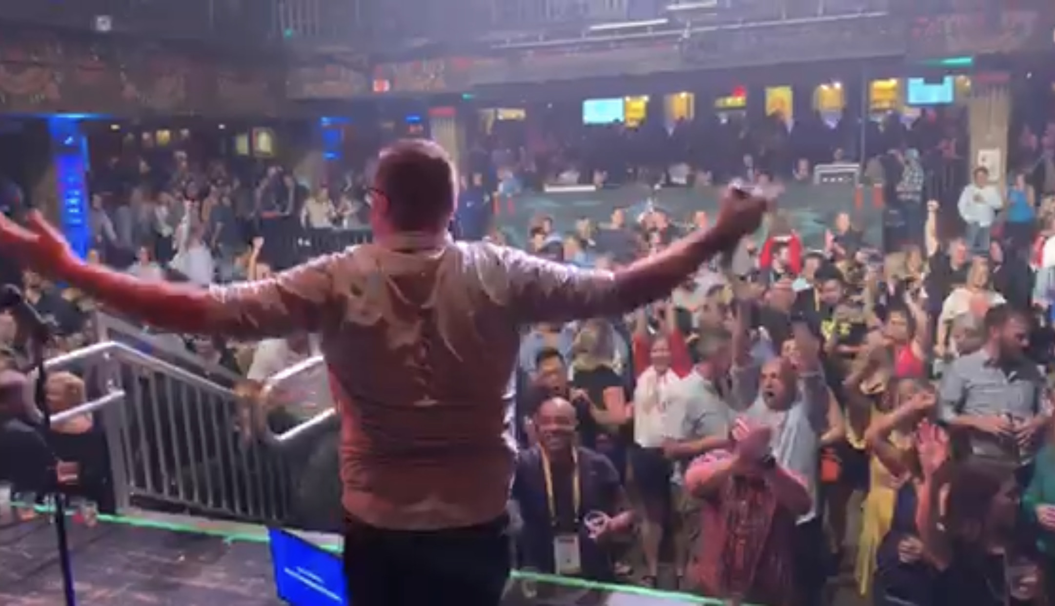 Jon on stage with arms raised to a massive cheering crowd at a tech conference