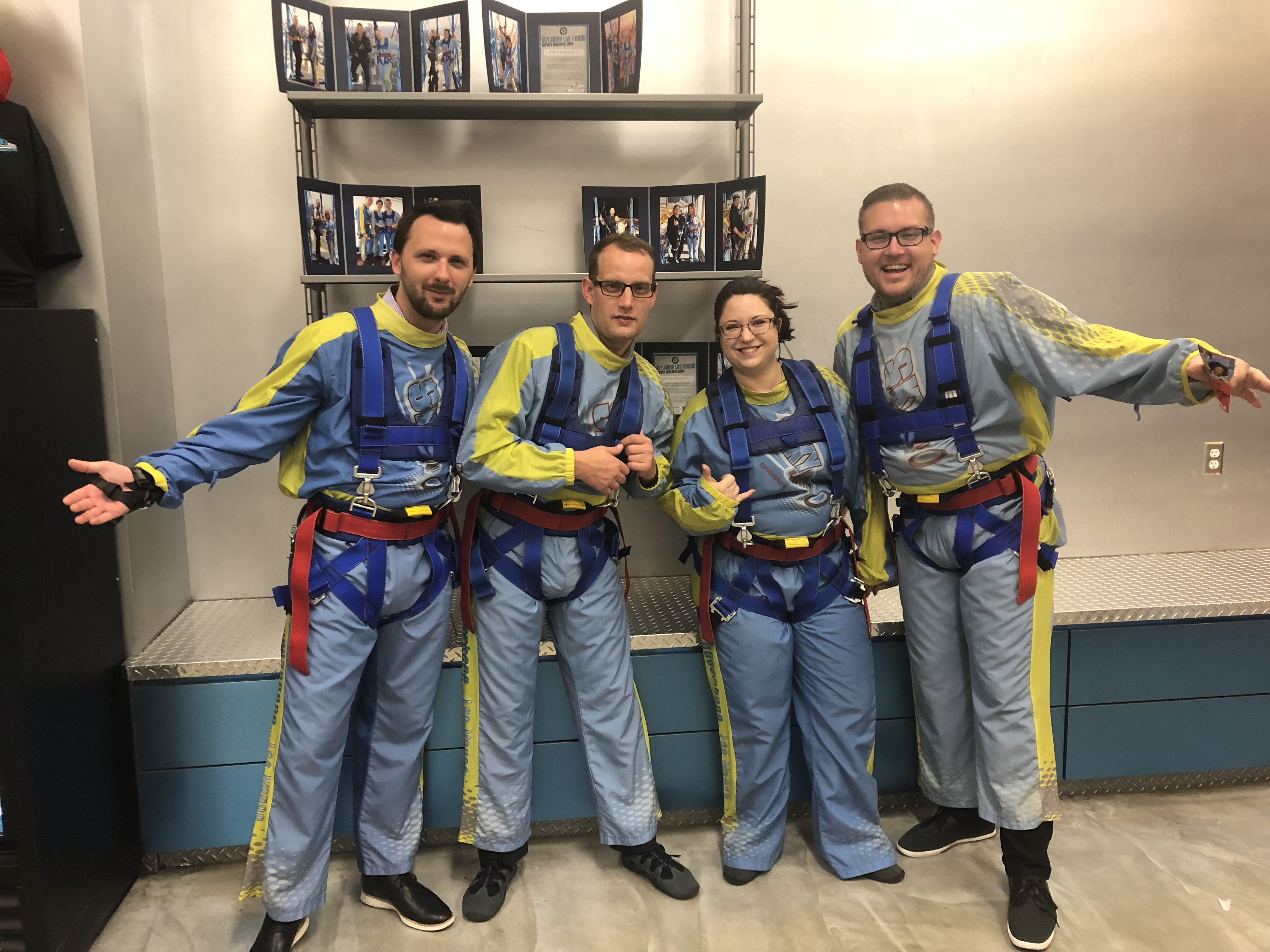 Jon and three friends in colorful skydiving suits, laughing before indoor skydiving