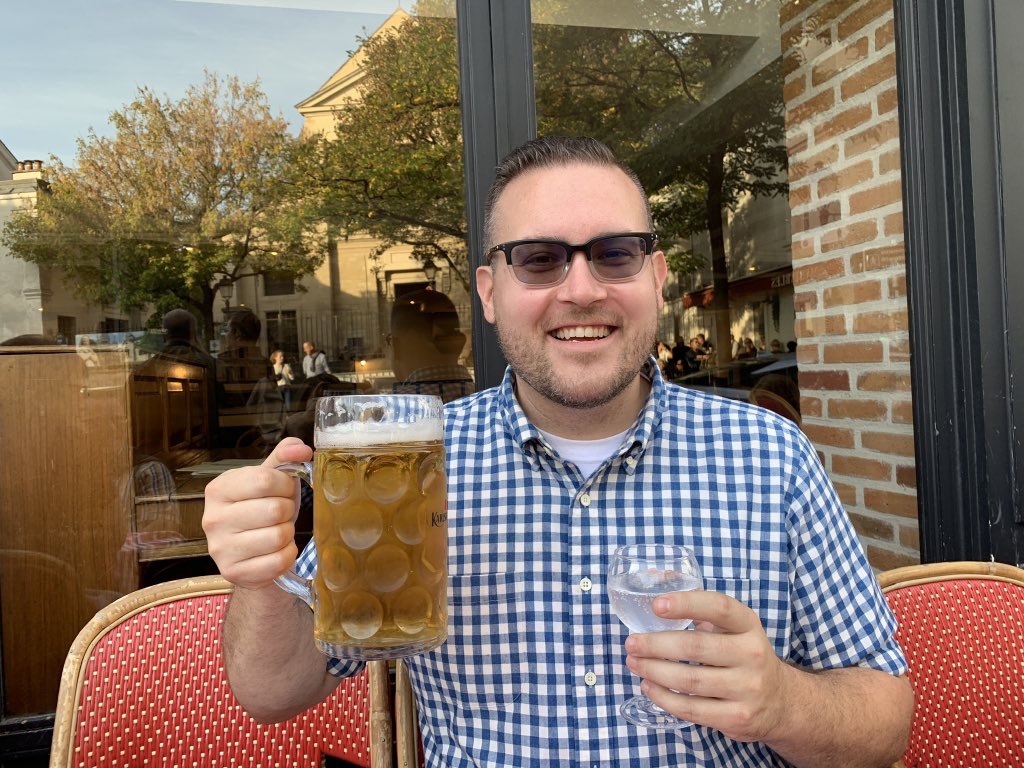 Jon at a French cafe holding a giant beer stein with a big smile